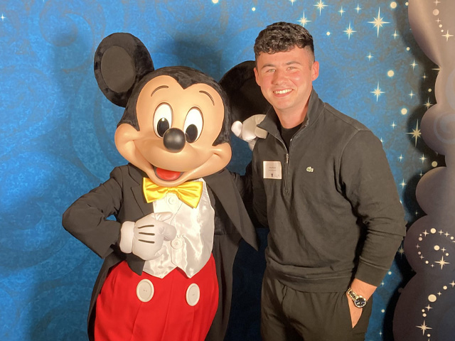 A man poses with Mickey Mouse
