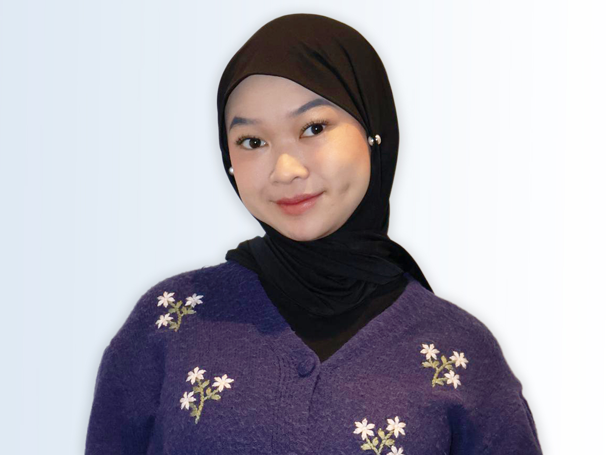 The Walt Disney Company Asia intern Hannah smiling while wearing a black hair and head covering and a blue sweater with white flowers
