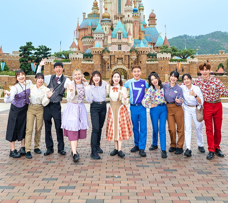 group of colleagues in colorful uniforms and costumes standing in front of a castle