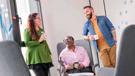 Three colleagues smiling and discussing together in a professional space