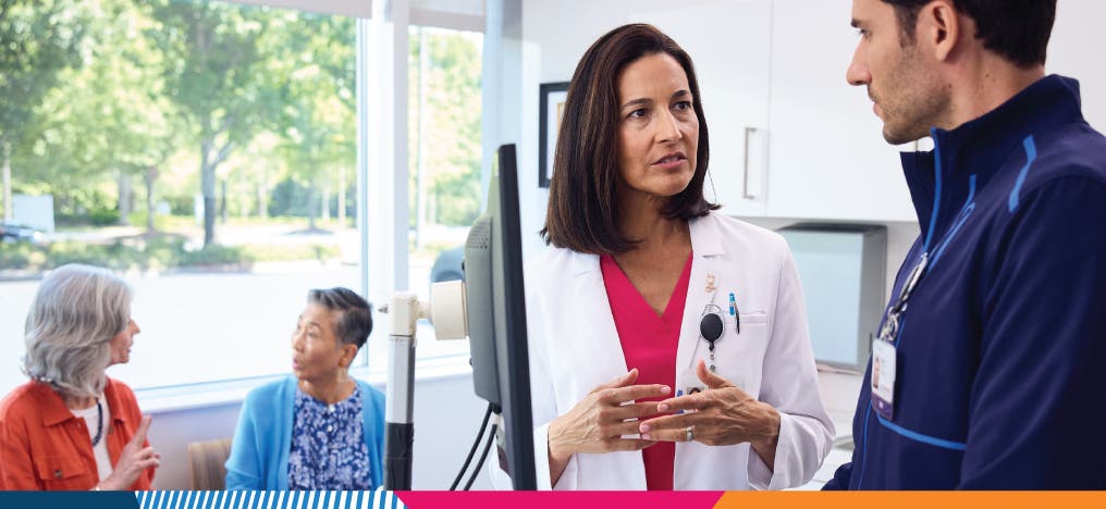 Two providers having a conversation at a computer EHR station in a medical office