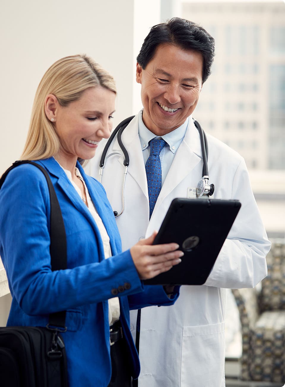 Field reimbursement manager reviewing data on a tablet with provider in a clinic setting.