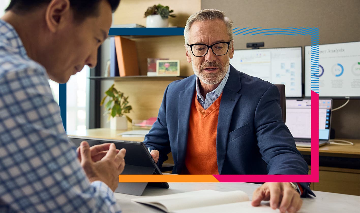 Pharma decision-maker seated in office with colleague, reviewing paperwork and data.