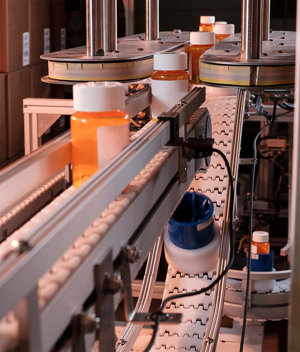 Pill bottles moving through a conveyer belt at a central fill facility