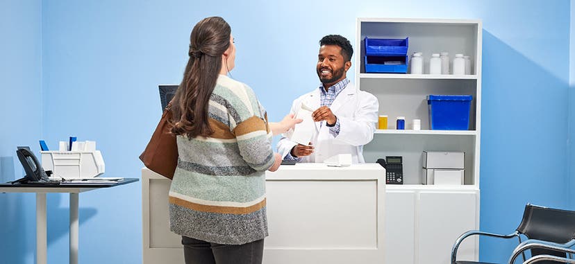 Image of a pharmacist handing a prescription to a patient at a pharmacy counter