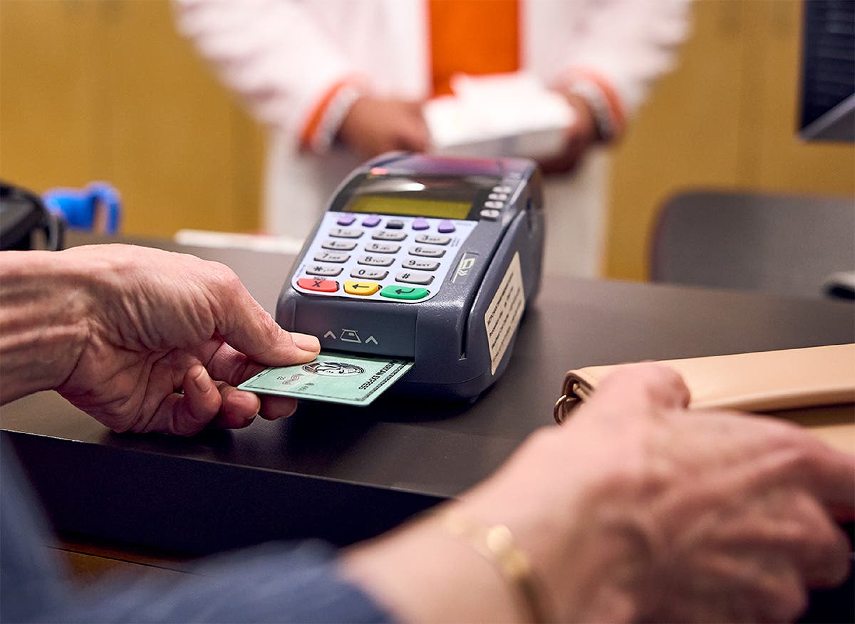 Patient at the pharmacy counter using credit card to pay for medications.