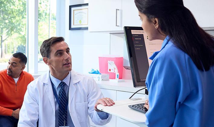 A provider speaking with a pharmacist at a computer