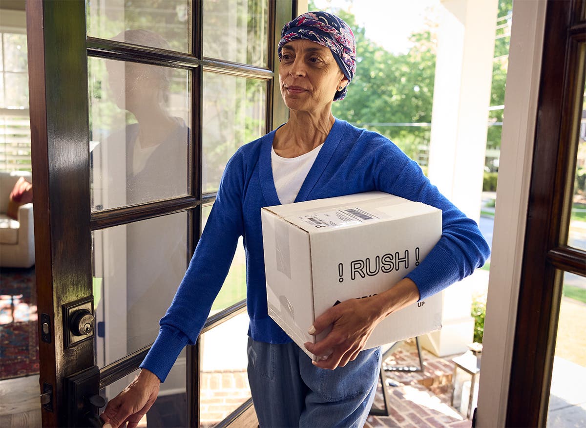 Patient entering home with box of mailed prescription medication.