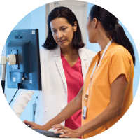 A provider and a nurse consulting in front of a computer and EHR.