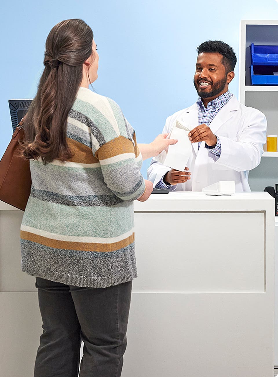 Patient receiving medication bag from pharmacist