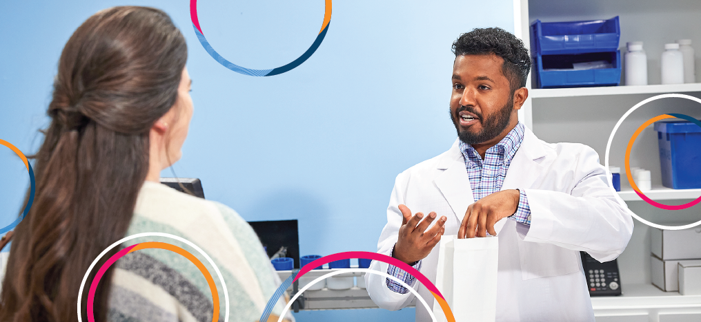 A healthcare provider kneels down to consult a patient receiving treatment in an arm chair