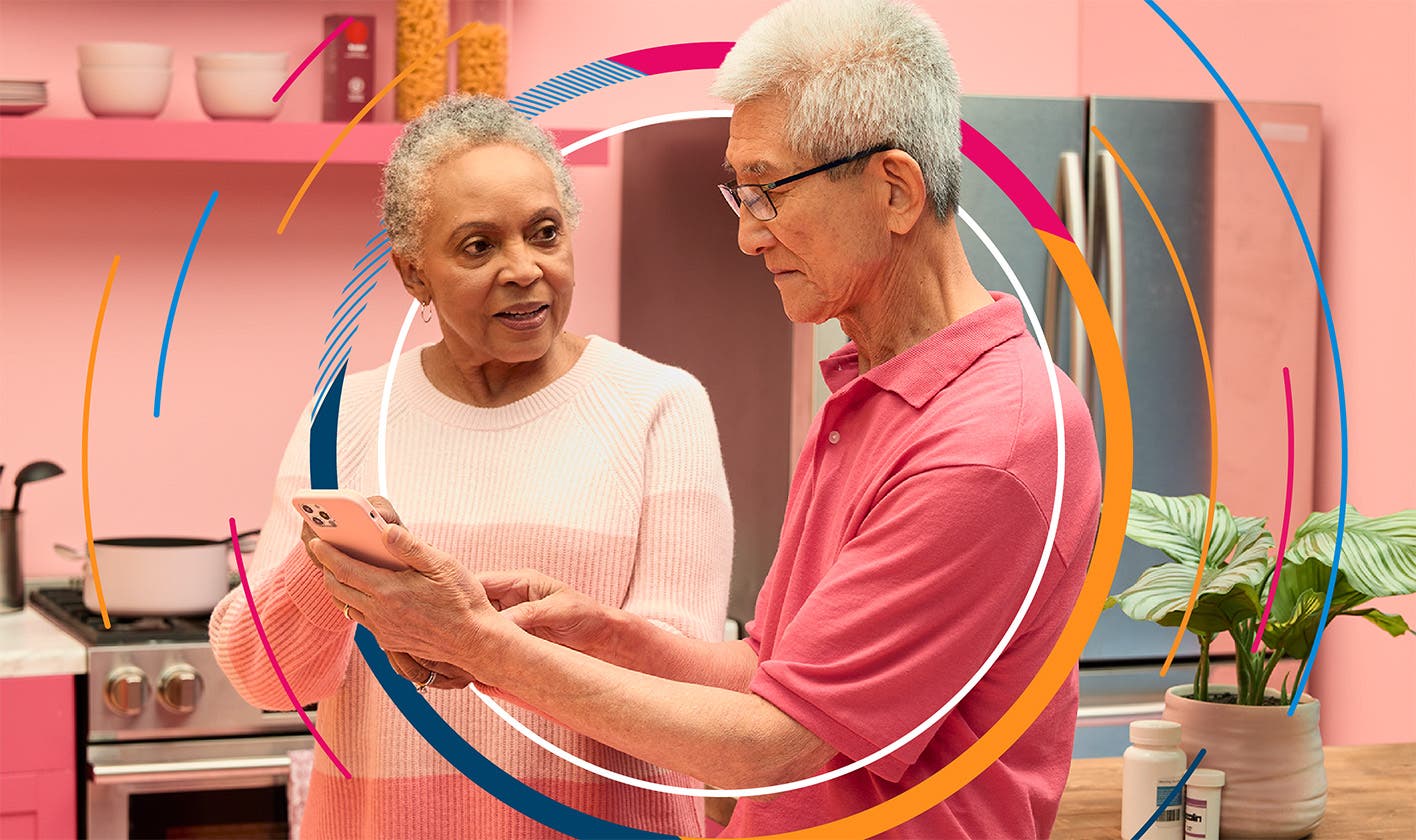 A couple relaxing at home use their cell phone to explore patient support services.