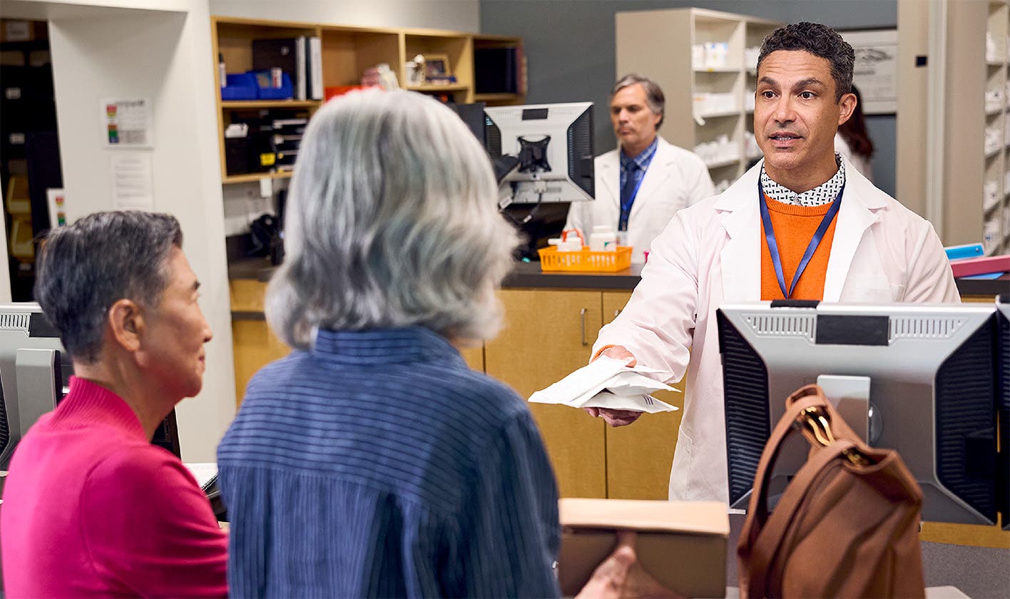 Pharmacist handing over prescription to a patient at a hospital outpatient pharmacy counter