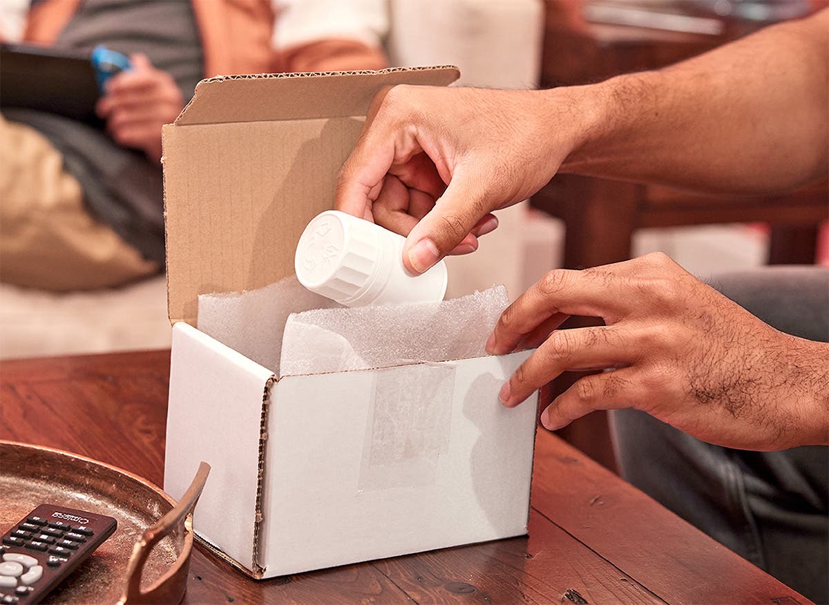 Patient removing medication bottle from a box in a home setting.