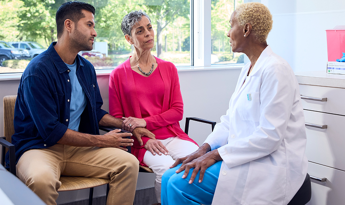 A provider consulting with two patients in front of a big window in a doctor's office