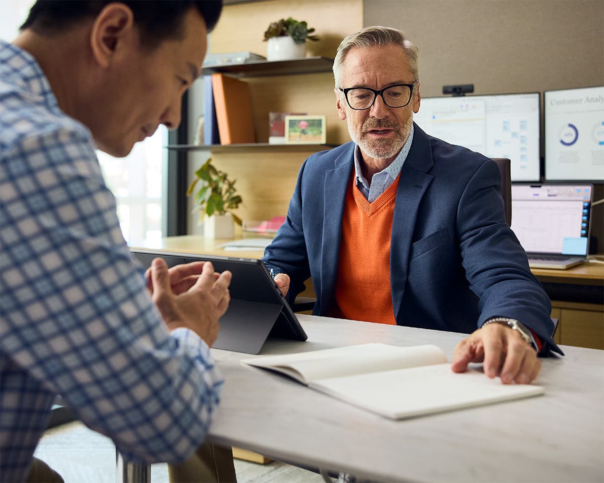 Pharma decision makers collaborating in an office reviewing data on a tablet.