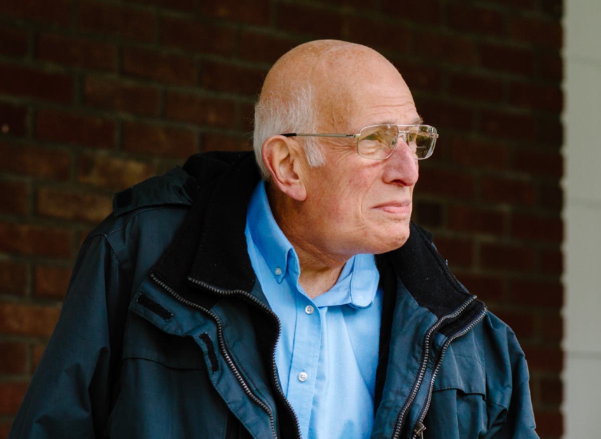 A gentleman stands on his porch, gazing into the distance.