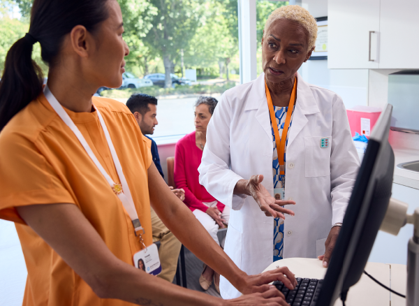A photo of a doctor consulting a nurse at a computer