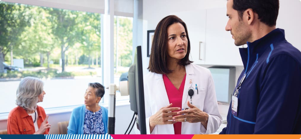 Two providers having a conversation at a computer EHR station in a medical office