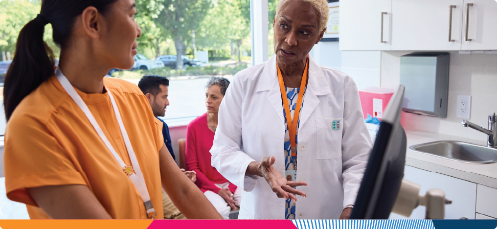 A nurse and a doctor consulting one another in front of a computer in a doctor's front office