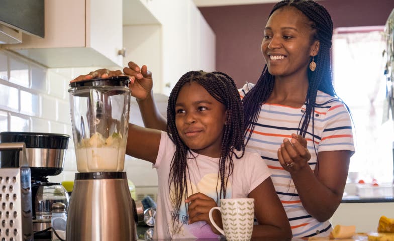 Mother and child playfully making a milkshake in a blender