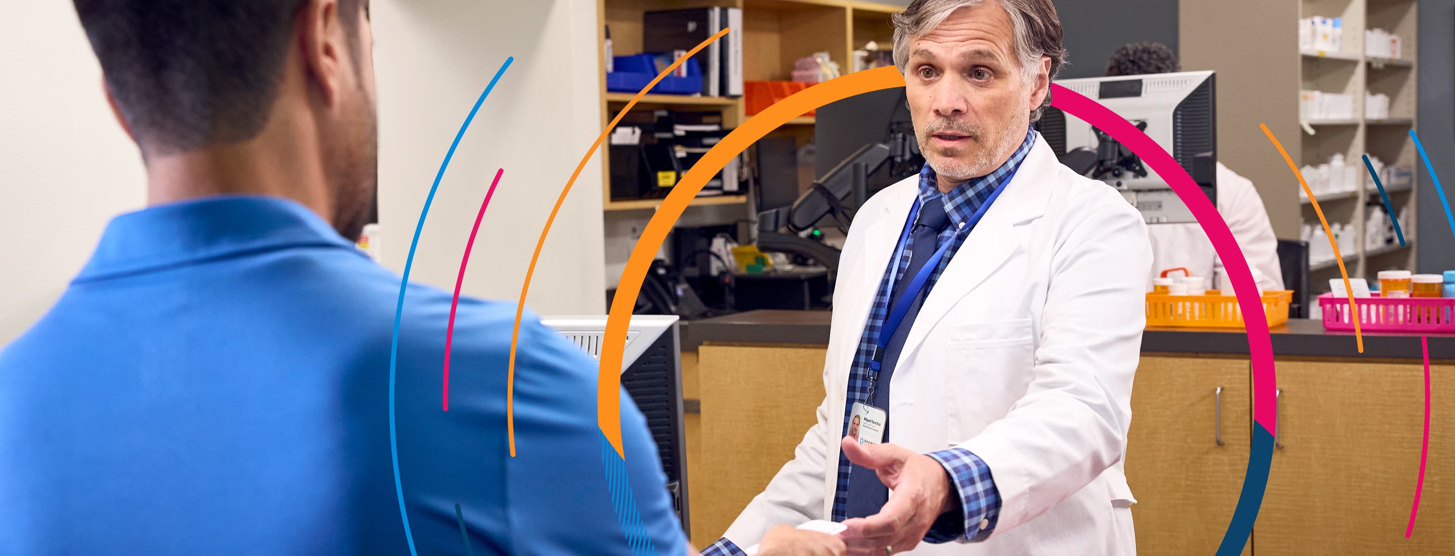 A pharmacist speaking to a patient while reaching to grab a card from his hand.