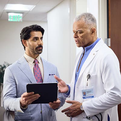 A FRM consulting a provider on a tablet in the hallway of a doctor's office