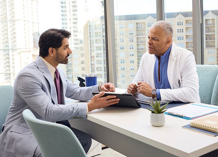 A photo of a provider and a corporate executive sitting in a board room.
