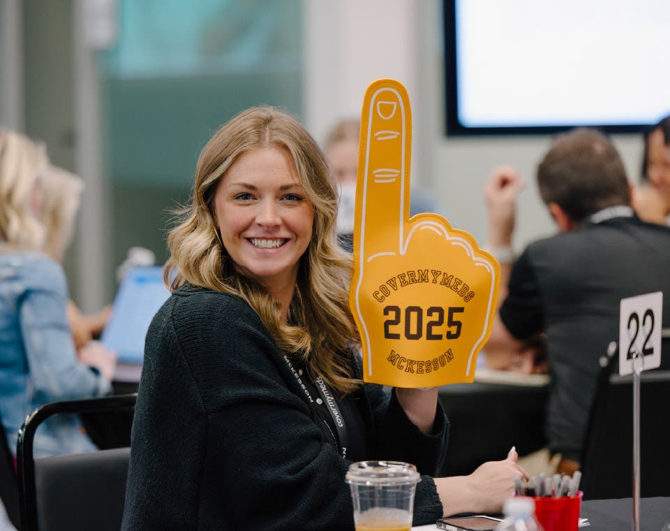 Employee smiling at the camera, holding a Number One foam finger on her hand