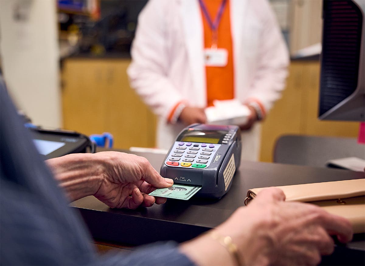 Patient uses credit card to pay for medication at the pharmacy counter