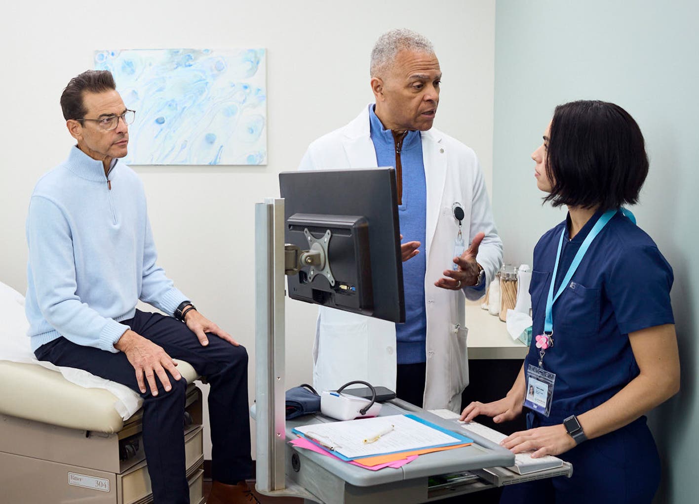 two providers talking in front of a computer while a patient looks on