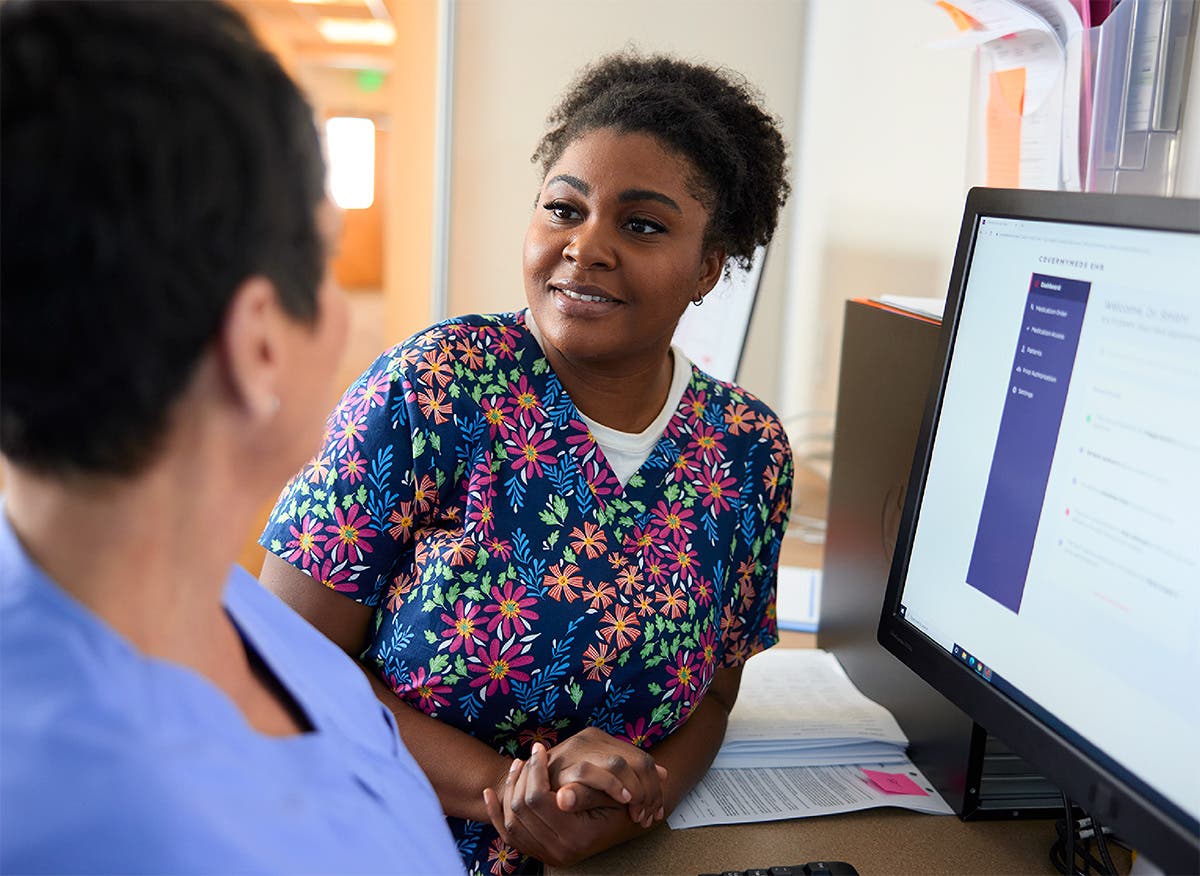 Care team members collaborating at a workstation reviewing an EHR dashboard.