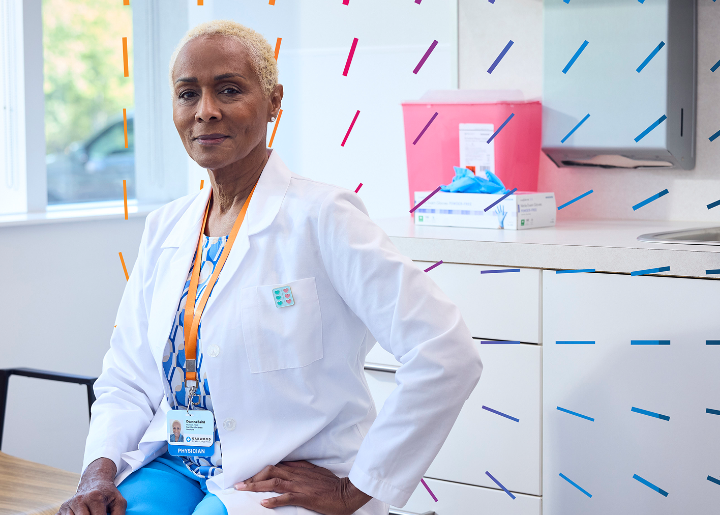 A photo of a physician in a lab coat sitting in a doctor's office setting