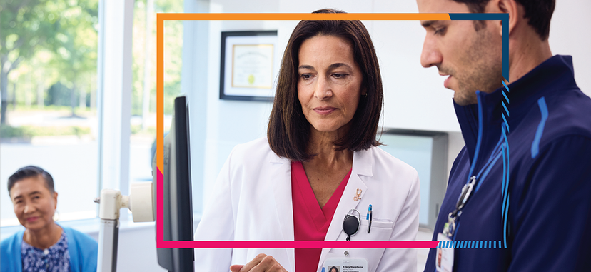 Image of a provider assisting another office member on a computer