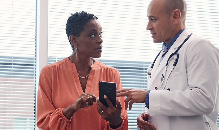 A provider explaining something on a smartphone screen to a patient