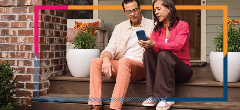 Two patients sitting on a porch, looking at a smartphone together.