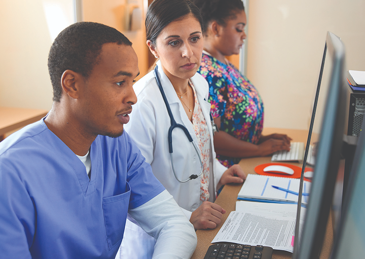 Three medical providers working on computers in a medical setting