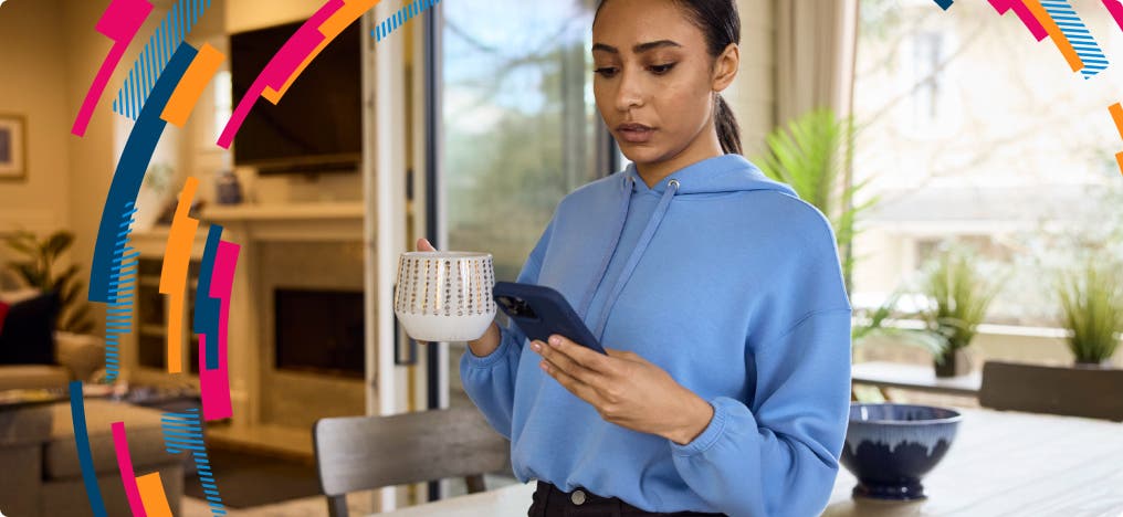 Woman checking her phone holding a cup of coffee at home with CoverMyMeds brand design colors in a circular frame